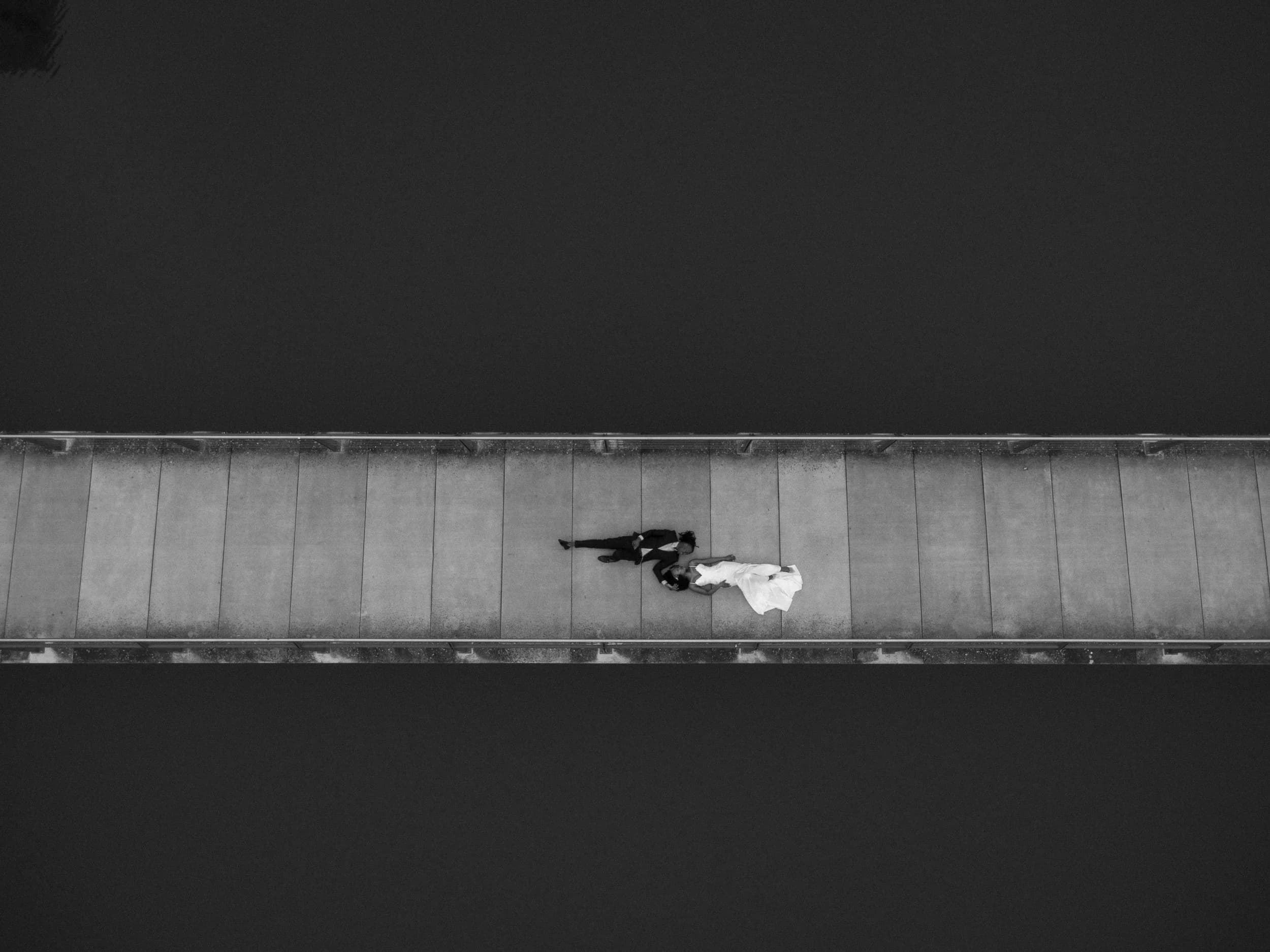Aerial view of bride and groom lying together on a pier